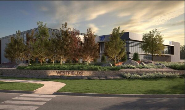 Modern office building named Westfields behind a landscaped stone wall and trees. sunset lighting.